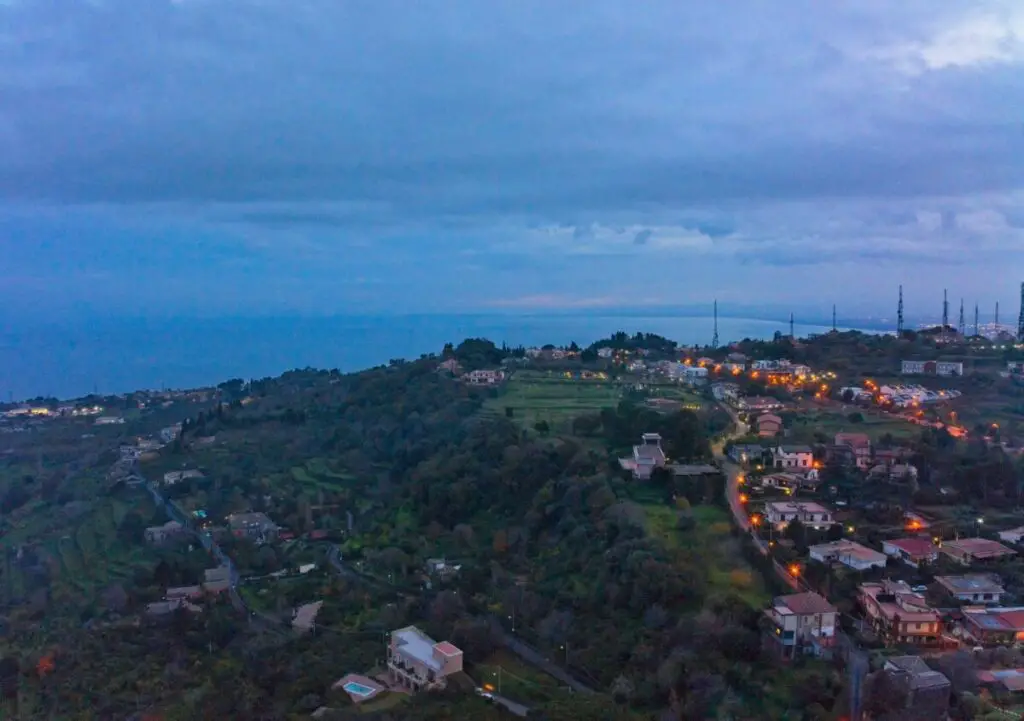 A village in Sicily over a hill overlooking the bay of Catania after sunset . Photo taken with a DJI Mavic 3 by Vicvideopic