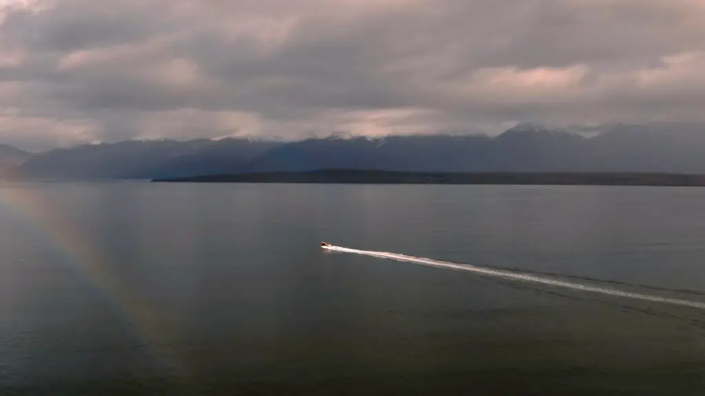 Aerial view of a small boat advancing in a fjord in Iceland, taken with a drone